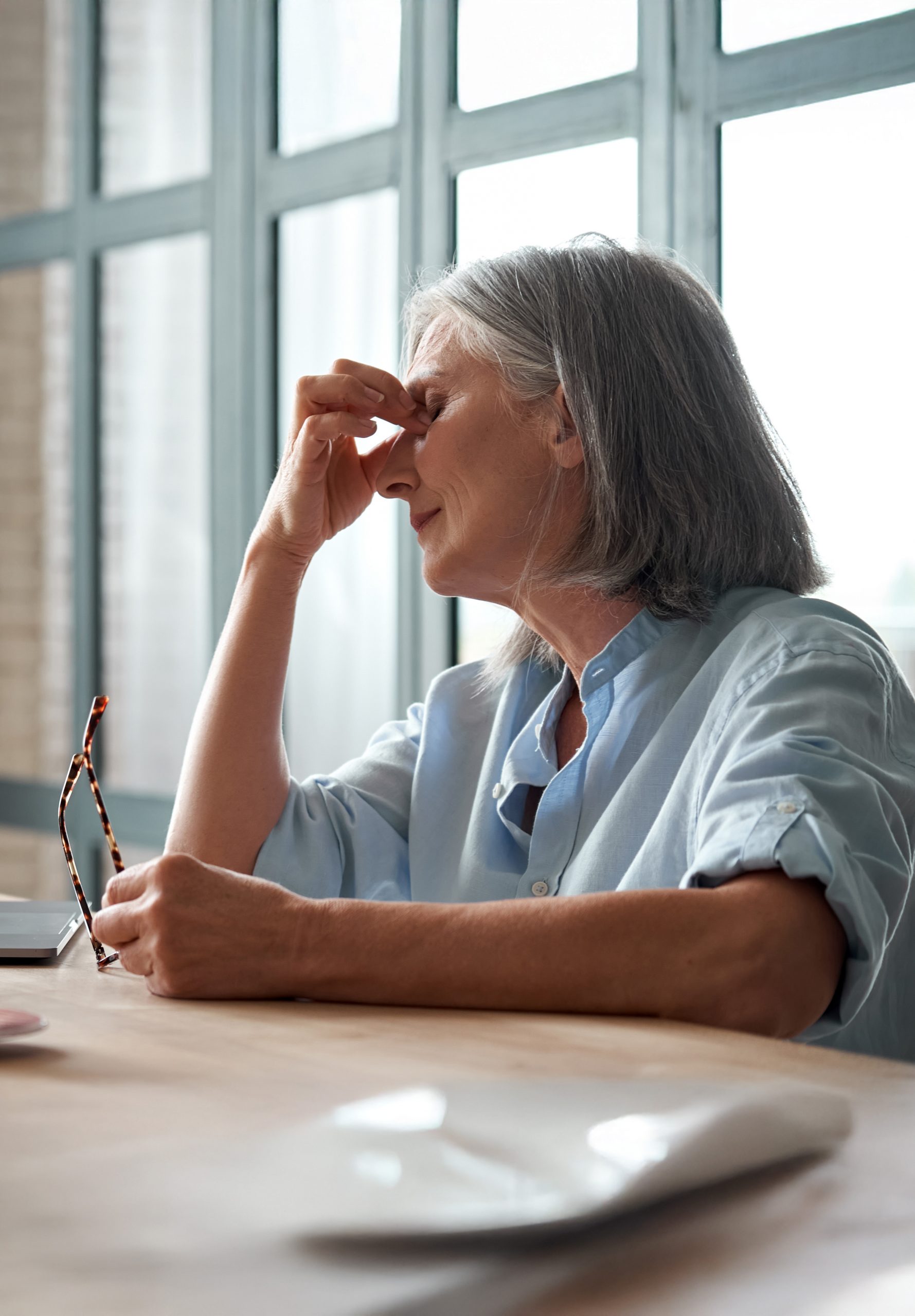 Tired old business woman takes off glasses feeling eye strain from computer.